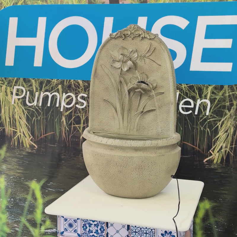 Floral wall mounted water feature with flower and dragonfly design, stone-look finish and rounded basin for indoor or outdoor use